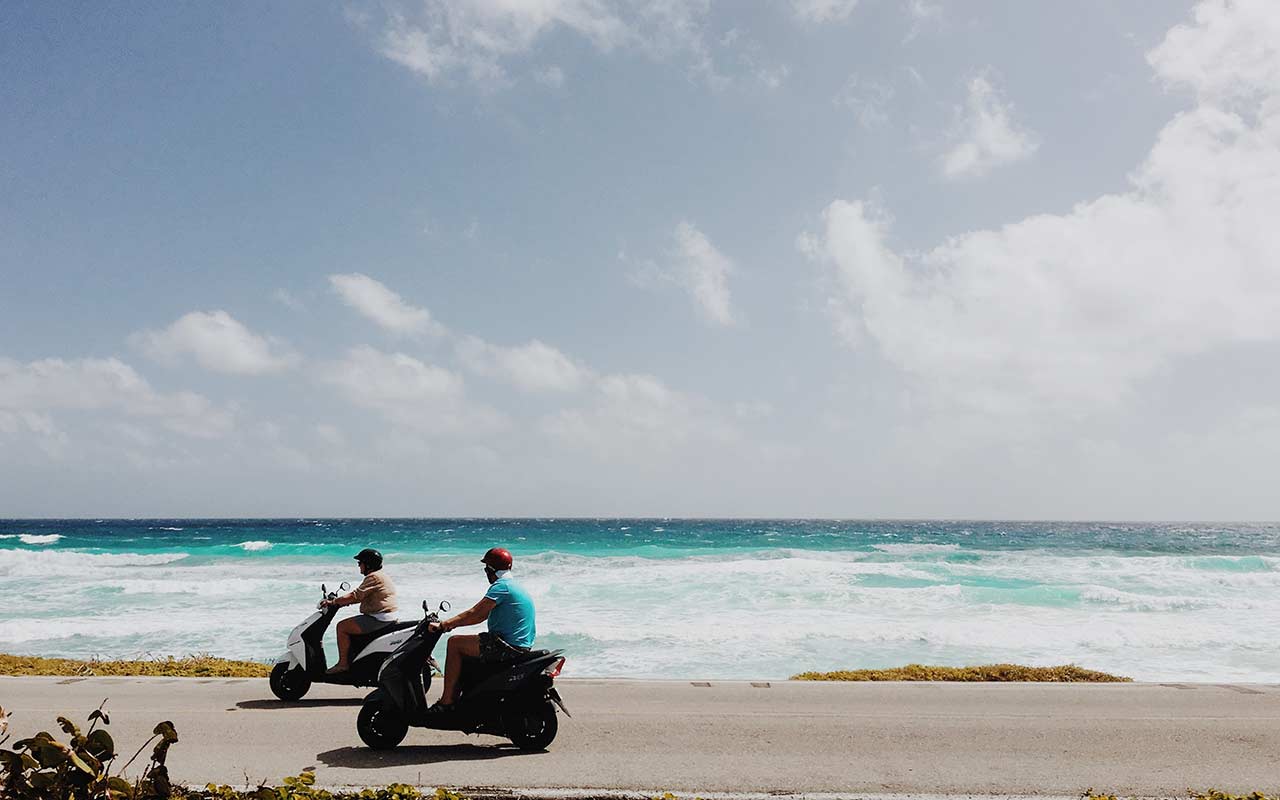 Backpackers touring the coast of Isla Cozumel with a motorcycle