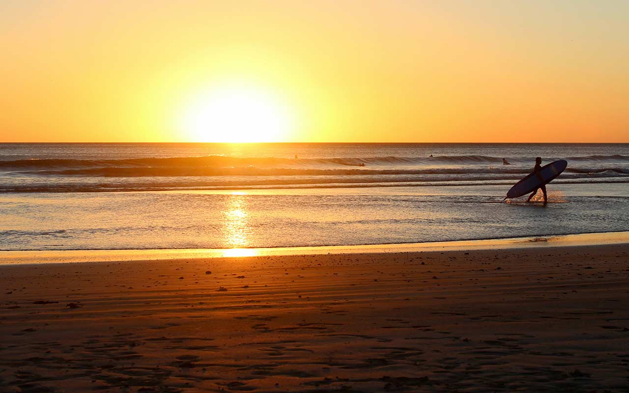 A surfer who ends his day after the sun sets at San Juan del Sur